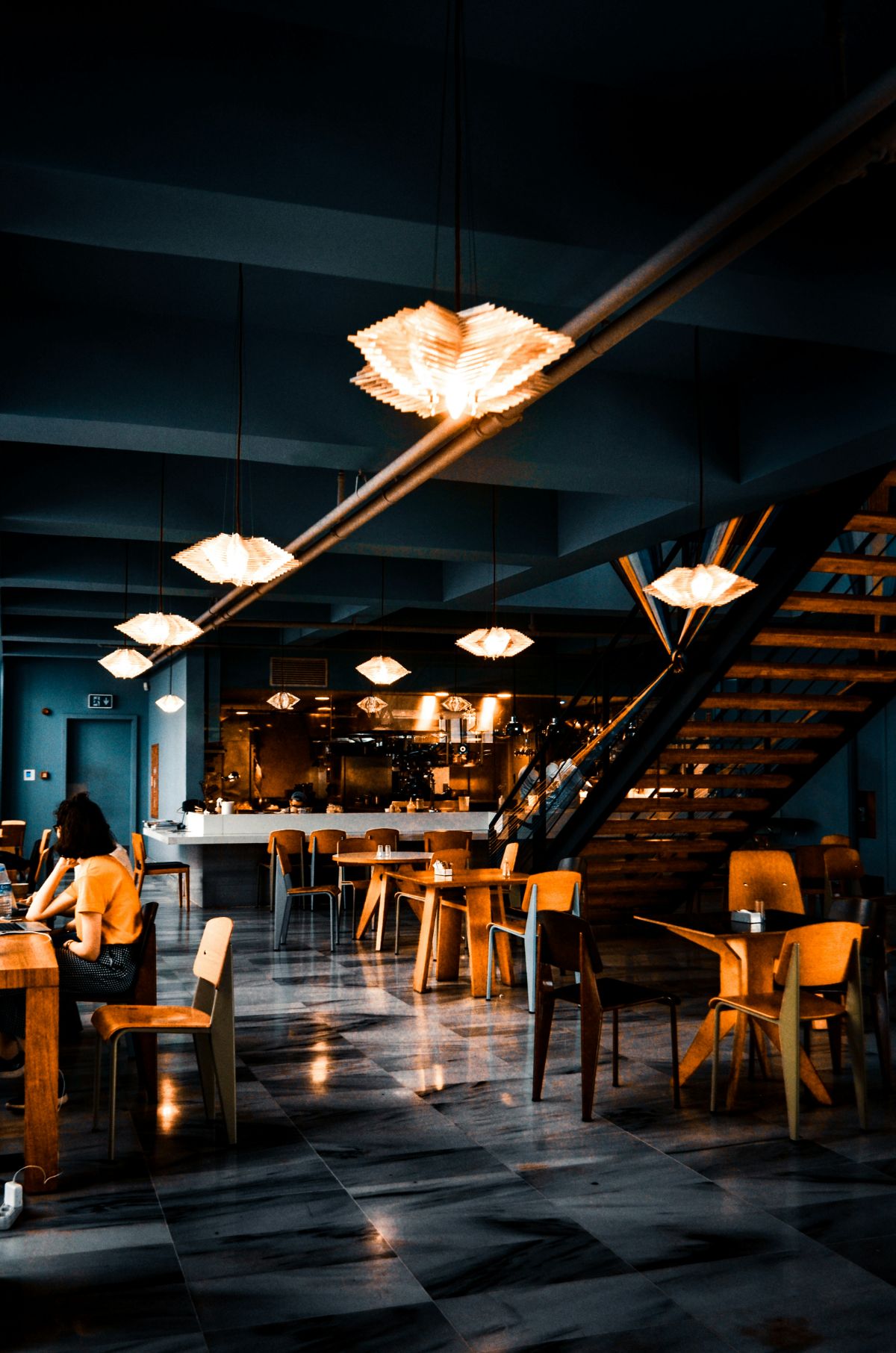 Low-lit dining room with pendant lighting and an open kitchen